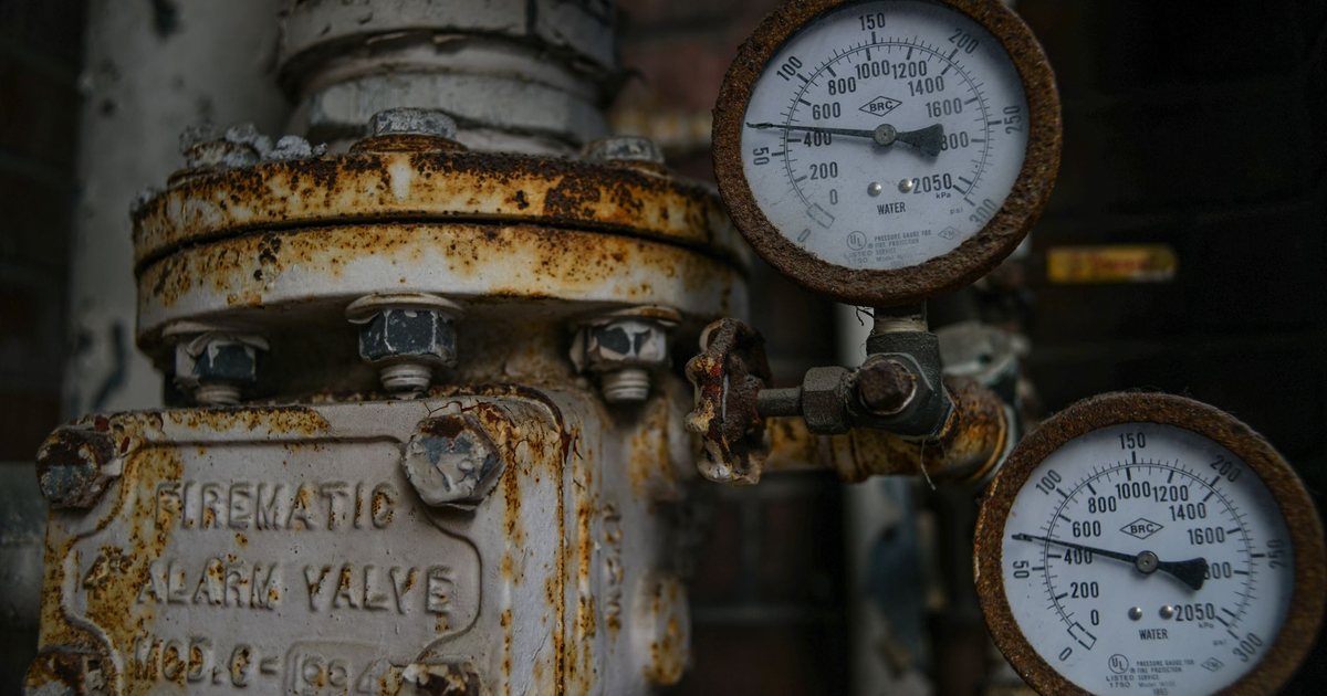 Rusted pipes, a pneumatic alarm valve and pressure gauges in an old plant room